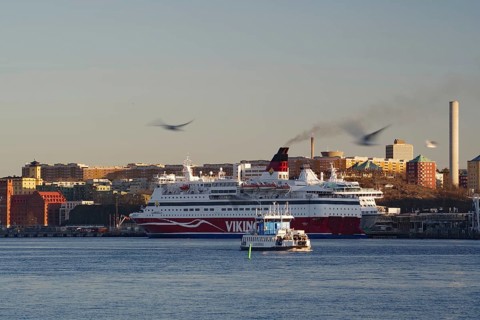 A ferry and a smaller city ferry on a river with an urban backdrop at dusk, Stockholm, Sweden