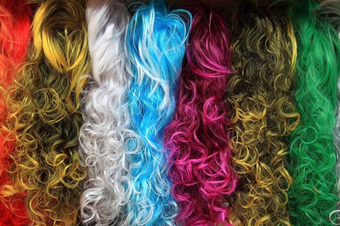 Colourful selection of long, curly wigs or hairpieces in various bright shades
