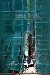Construction site, house with scaffolding and a net in front of it as dust protection, waste tunnel