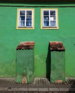 Green house façade with two small windows in the old town of Sighisoara, German Sighisoara, town in
