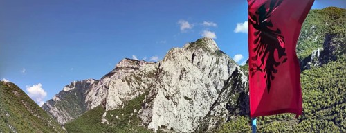 Mountain landscape with the Albanian flag against a clear sky and impressive rock formations, Peaks