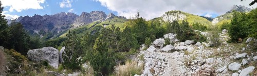 Panorama, rocky path surrounded by trees and mountains under a partly cloudy sky, Peaks of the
