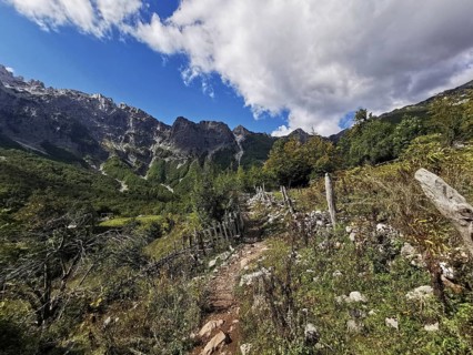 Rocky hiking trail along a hill surrounded by mountains under rugged skies, Peaks of the Balkans,