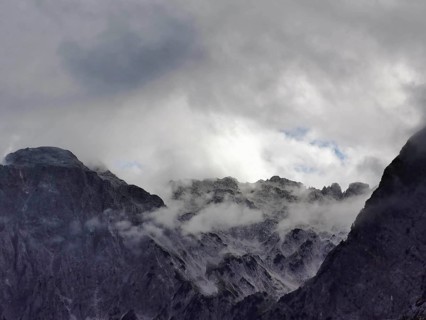 Dramatic cloud formations over rocky mountain peaks, mostly in shades of gray, Peaks of the