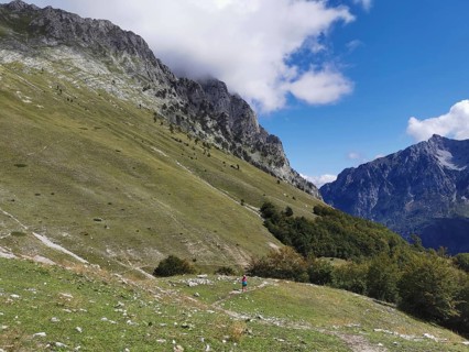 Extensive alpine landscape under a cloudy sky next to imposing mountain slopes, Peaks of the