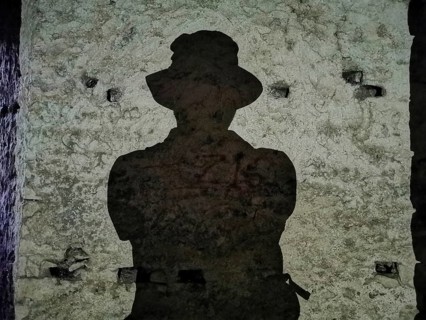 A dark shadow silhouette of a person wearing a hat on an old stone wall, Albania