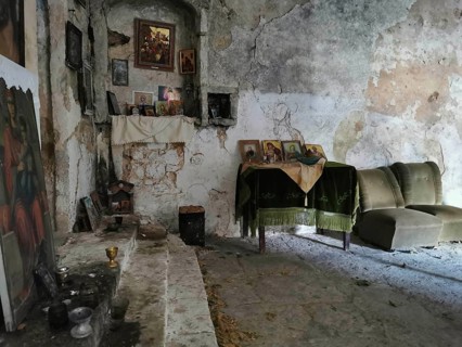 Atmospheric interior view of an abandoned Orthodox chapel with icons and dilapidated walls, Himare,