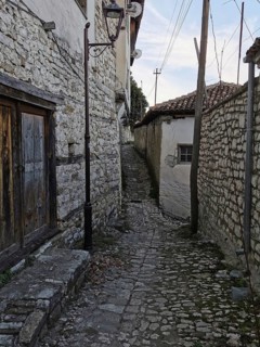 Narrow, cobblestone alley with old stone walls and traditional houses, old town of Berat, Albania