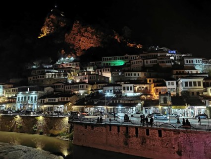 Night view of an illuminated city on the slope of a hill with river in the foreground, Berat,