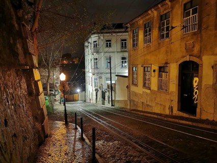 Night view of a picturesque street with cobblestones and buildings illuminated by lamps, tracks of