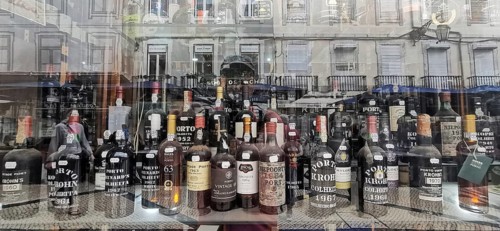 Old port wine, wine bottles and spirits in a shop window with city reflections in the background,