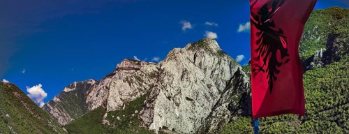 Alpine landscape with an Albanian flag and majestic mountains under blue sky, Peaks of the Balkans,