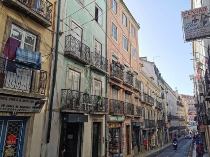 View of a street with colorful buildings, laundry hanging on wrought iron balconies in Lisbon, Old
