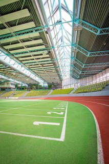 Extensive sports hall with green running track and stands, large windows, Sindelfingen Glass