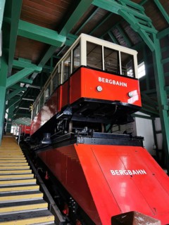 A red mountain railway is located in a covered area surrounded by green wooden structures,