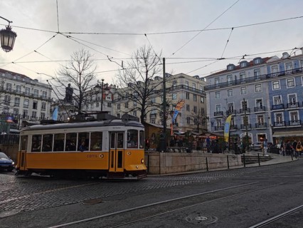 A yellow, historic tram stands in the city center at dusk, Lisbon, Portugal