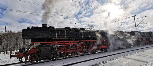A historic steam locomotive emits smoke while standing on tracks in winter, Rennsteig, Frankenwald