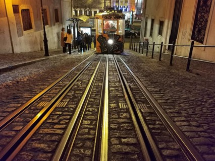 Front view from track perspective, graffiti-painted funicular runs illuminated through the night,