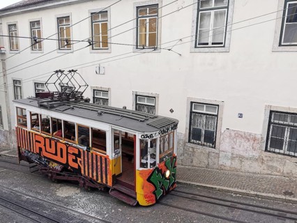 Historic funicular, Elevador da Gloria with colorful graffiti goes down a steep road, Lisbon,