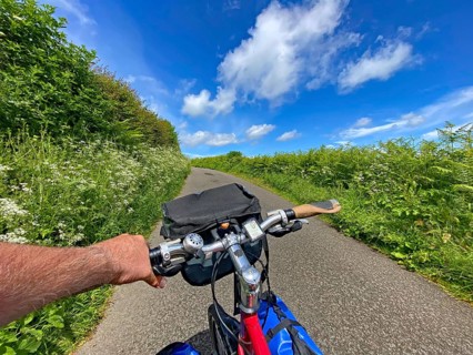 View of a bike ride along a green path under clear blue sky, Highlands, Scotland, Great Britain