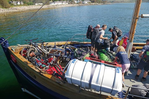 People loading a boat with bikes and luggage on a clear summer day in the harbour, Knoydart,
