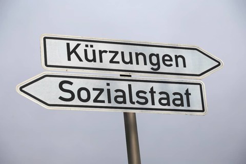 (photo montage) Directional arrows against a grey sky point in the directions of CUTS and WELFARE