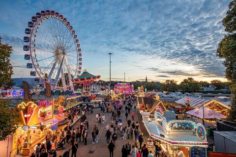 Ferris wheel, chain carousel, food stalls and visitors at the Cannstatter Volksfest, Cannstatter