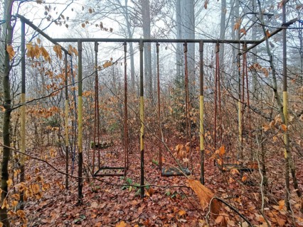 An abandoned playground in autumn forest with rusty climbing frame and autumn leaves, Thuringian