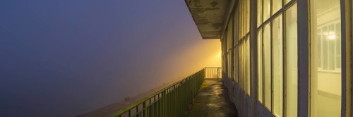 View along a long balcony of Steubenhöft at night in fog, Cuxhaven, Lower Saxony, Germany