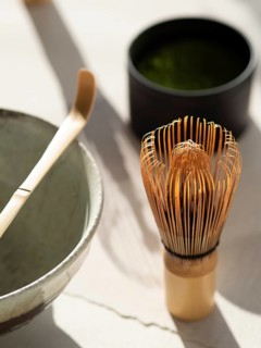 Preparing matcha green tea with traditional chasen, chawan, and chashaku on a bright table