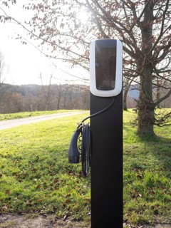Ev charging station standing in green grass, promoting sustainable transportation