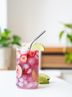 Glass of sparkling water with strawberries, lime, and ice, ready for drinking