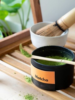 Green tea matcha powder spilling from a measuring scoop on a wooden tray