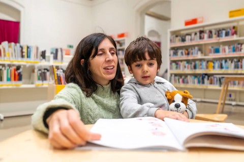 Mother and young son enjoying quiet time together in a public library, actively participating in a