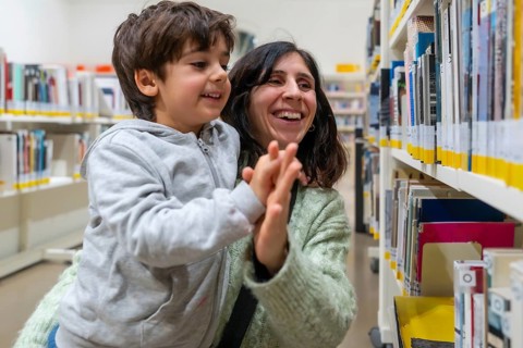 Parent and young child are sharing a joyful high five gesture while standing in a brightly lit