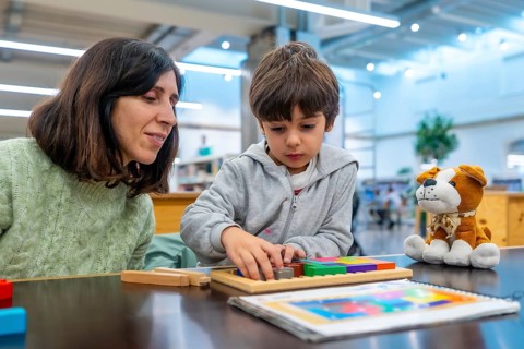 Teacher and young boy engaging in educational play, carefully fitting colorful geometric blocks