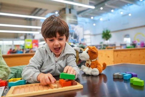 Young child experiencing joy and concentration while playing with colorful wooden building blocks