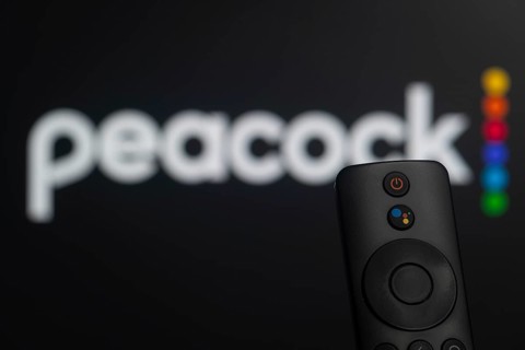 Dhaka, Bangladesh- 21 Jan 2026: Close-up of a smart TV remote control against a blurred peacock