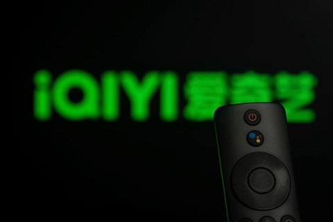 Dhaka, Bangladesh- 21 Jan 2026: Close-up of a smart TV remote control against a blurred iQIYI logo