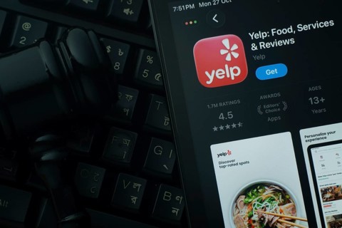 Dhaka, Bangladesh- 28 Oct 2025: An iPad displaying the Yelp app against a judge's gavel and dark