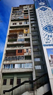 The colorful façade with windows, balconies, laundry, of a tall, old, partly dilapidated