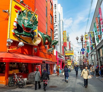 Dragon figure at a restaurant, lots of colorful signs in a pedestrian zone with shops and