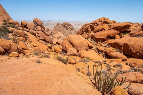 Rocky desert landscape with scattered vegetation in Spitzkoppe under a blue sky, Spitzkoppe,