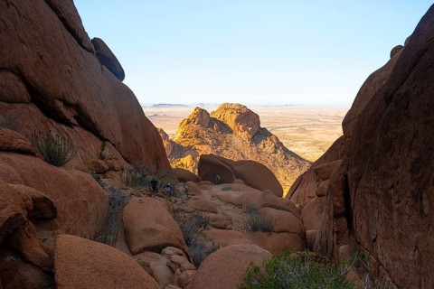 A crevice between rocks opens up a view of the dry desert landscape, Spitzkoppe, Namibia