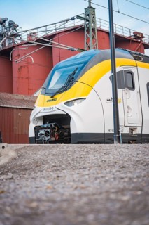 Modern locomotive on rails against an industrial backdrop under grey skies, opening of the Hermann