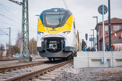 Modern locomotive on railroad tracks in front of buildings and power lines, opening of the Hermann