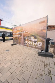 Advertising banner for the Hermann Hesse Railway on a platform, with a train in the background,