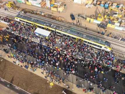 Dense crowd around a train on a construction site, taken from above, opening of the Hermann Hesse