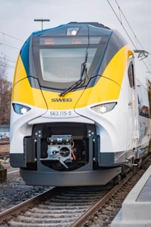 Close-up of the modern front of a white train with yellow elements, opening of the Hermann Hesse