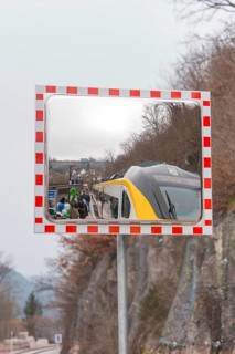 A train in the mirror on a railroad track in a mountainous area, opening of the Hermann Hesse